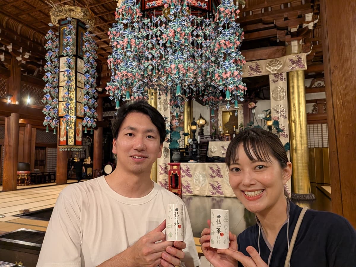 本堂にて、仏茶を手にする芸人みほとけchanとのひとこま